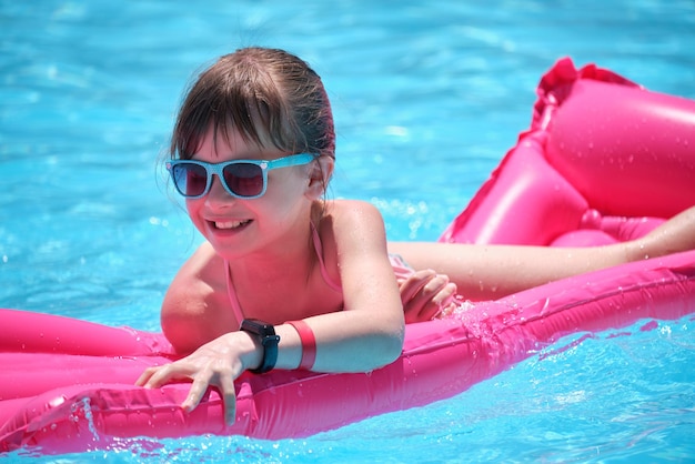 Young child girl falling in water from inflatable air mattress in swimming pool while swinnimg during tropical vacations Safety of aquatic activities concept