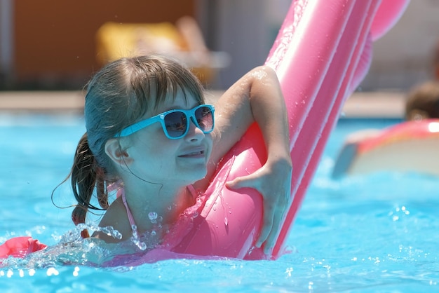 Young child girl falling in water from inflatable air mattress in swimming pool while swinnimg during tropical vacations Safety of aquatic activities concept