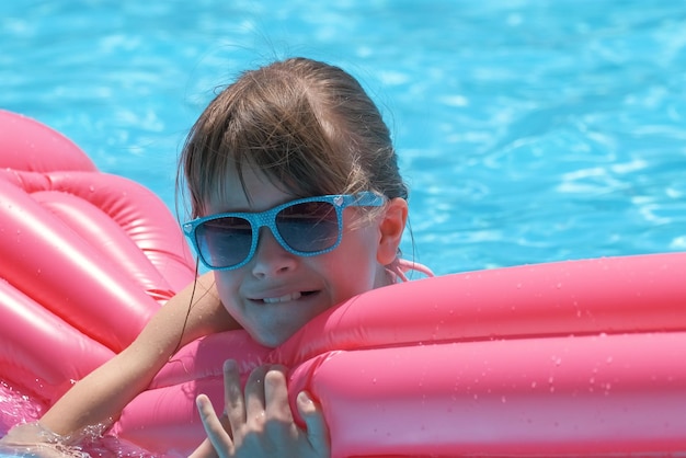 Young child girl falling in water from inflatable air mattress in swimming pool while swinnimg during tropical vacations Safety of aquatic activities concept