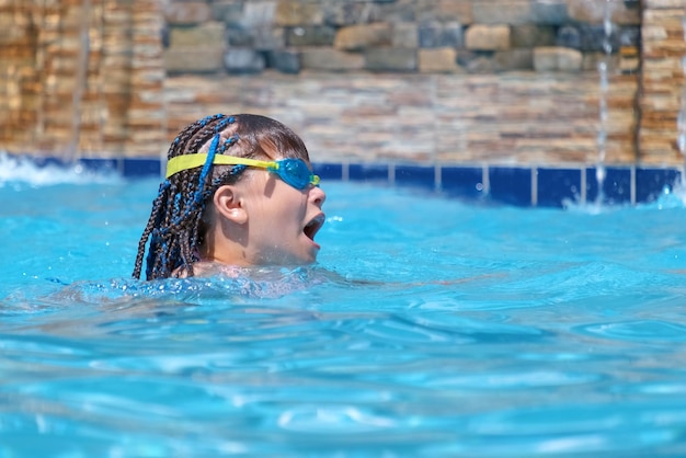 Young child girl in goggles exercises swimming in blue pool water Summer recreation activity concept