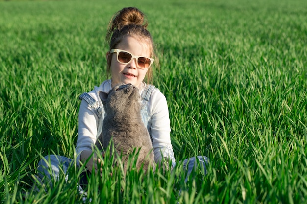 Young child girl having fun with cat at the garden