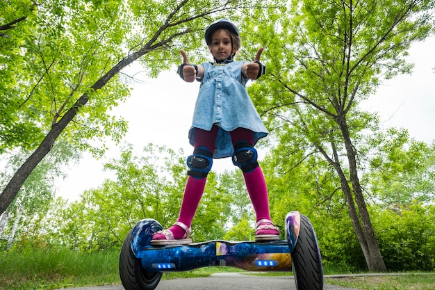 Young child girl riding in a city Park on gyroscooter Summer entertainment in nature Electric scooter is a modern ecofriendly mode of transport selfbalancing scooter healthy lifestyle