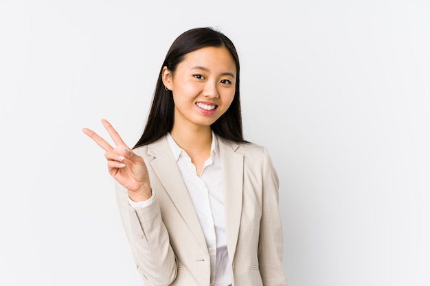 Young chinese business woman isolated joyful and carefree showing a peace symbol with fingers.