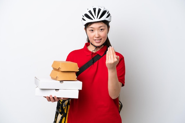 Young Chinese delivery woman taking takeaway food isolated on white background inviting to come with hand Happy that you came