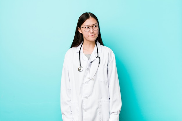 Young chinese doctor woman confused, feels doubtful and unsure.