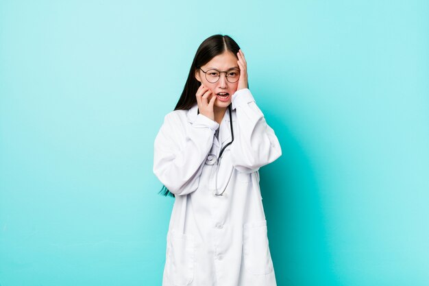 Young chinese doctor woman whining and crying disconsolately.