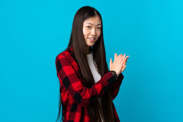 Young Chinese girl over isolated blue background applauding