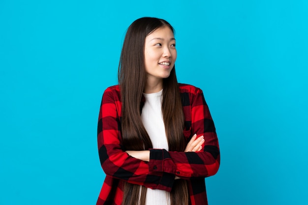 Young Chinese girl on isolated blue happy and smiling