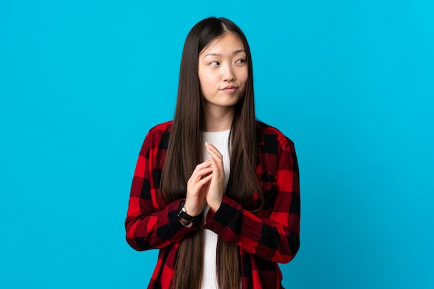 Young Chinese girl on isolated blue scheming something