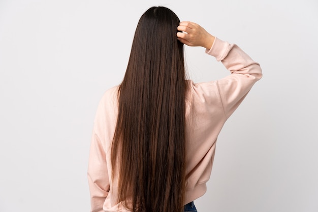 Young Chinese girl over isolated white wall in back position and thinking