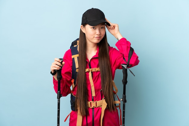 Young Chinese girl with backpack and trekking poles isolated