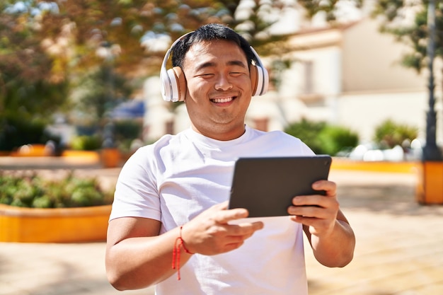 Young chinese man smiling confident watching video at park