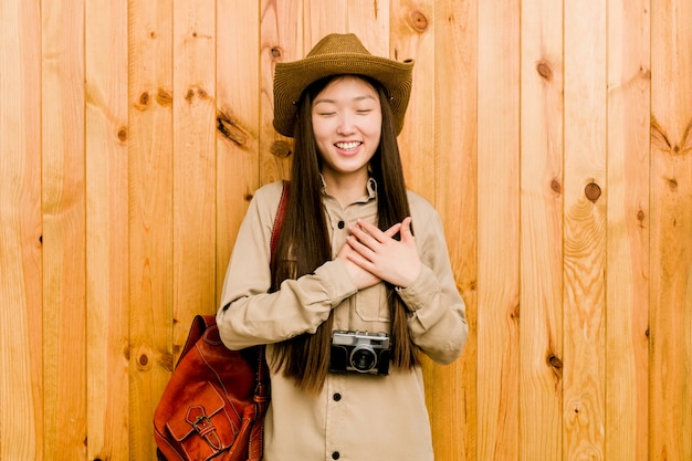 Young chinese traveler woman laughing keeping hands on heart, concept of happiness.