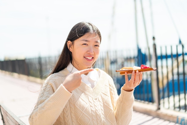 Young Chinese woman holding sashimi at outdoors and pointing it