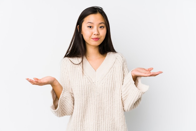 Young chinese woman isolated doubting and shrugging shoulders in questioning gesture.