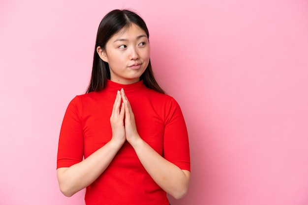 Young Chinese woman isolated on pink background scheming something