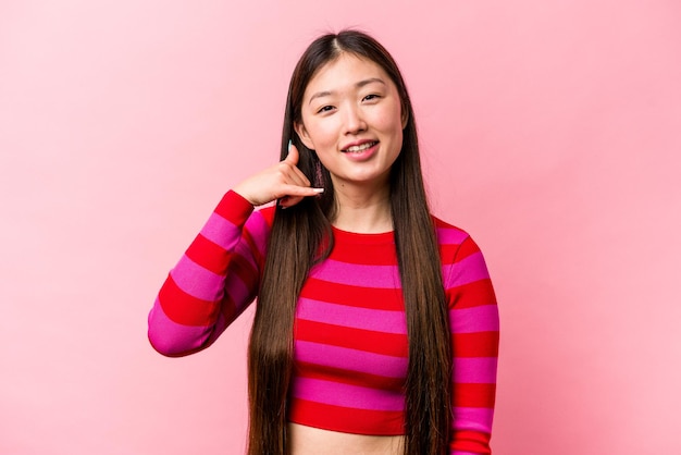 Young Chinese woman isolated on pink background showing a mobile phone call gesture with fingers