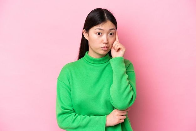 Young Chinese woman isolated on pink background thinking an idea