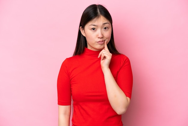 Young Chinese woman isolated on pink background and thinking