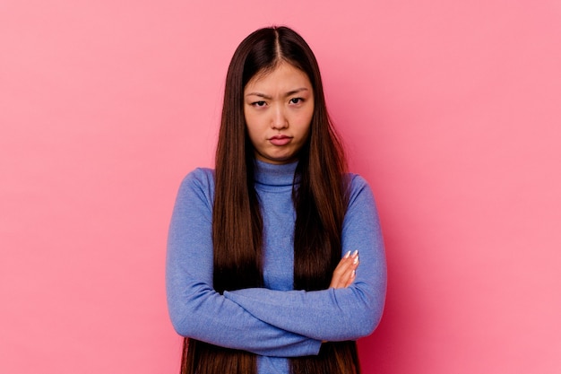 Young chinese woman isolated on pink wall blows cheeks, has tired expression. Facial expression concept.