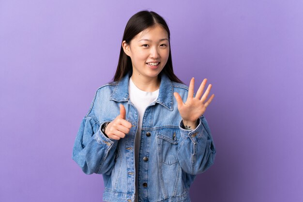 Young Chinese woman on isolated purple counting six with fingers