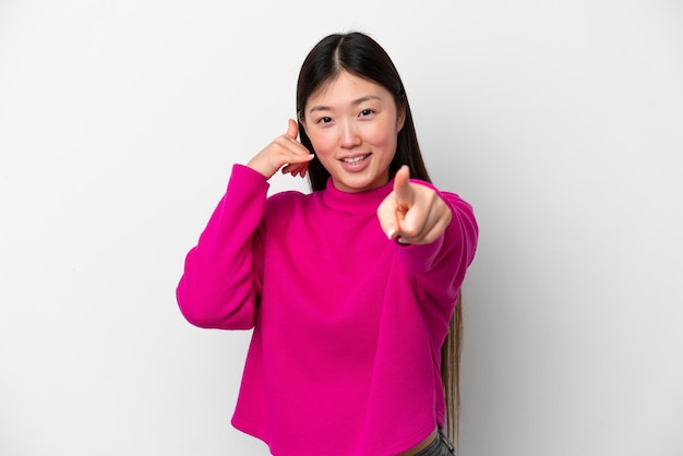 Young Chinese woman isolated on white background making phone gesture and pointing front