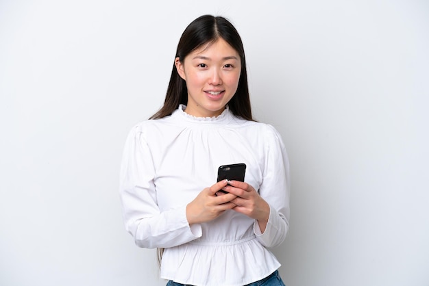 Young Chinese woman isolated on white background sending a message with the mobile