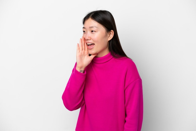 Young Chinese woman isolated on white background shouting with mouth wide open to the side