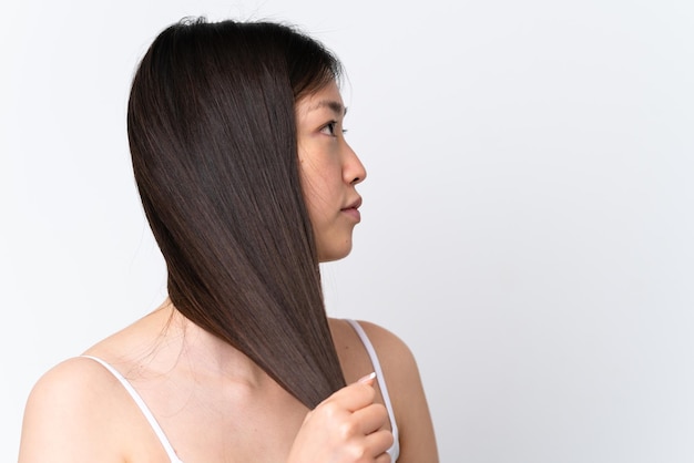 Young Chinese woman isolated on white background touching her hair Close up portrait