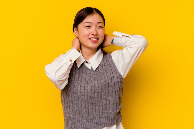 Young chinese woman isolated on yellow wall stretching arms, relaxed position