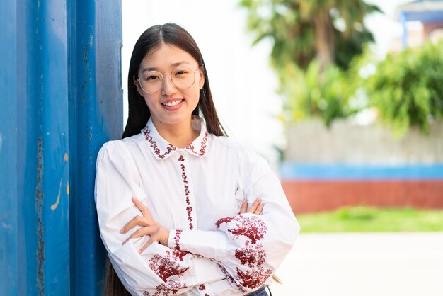 Young Chinese woman at outdoors With glasses with happy expression