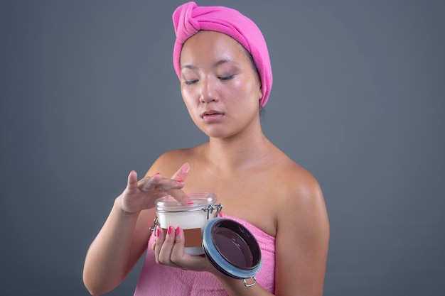 Young chinese woman taking care of her skin isolated from gray background beauty concept