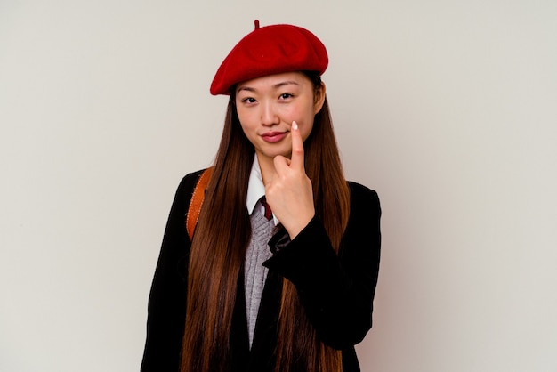 Young chinese woman wearing a school uniform  pointing with finger at you as if inviting come closer.