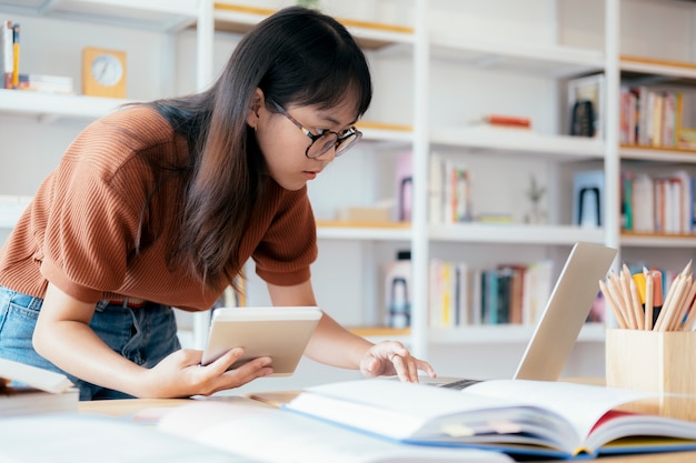 Young collage student using computer and mobile device studying online.