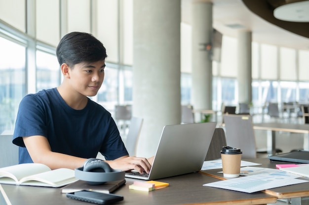 Young collage student using computer and mobile device studying online.