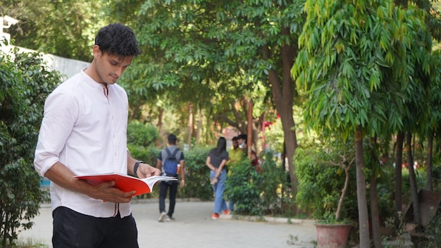 Young college boy with book at college campus