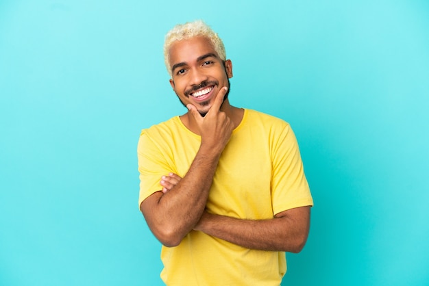 Young Colombian handsome man isolated on blue background happy and smiling