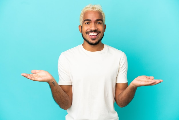 Young Colombian handsome man isolated on blue background with shocked facial expression