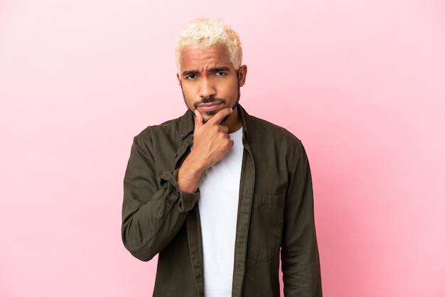 Young Colombian handsome man isolated on pink background thinking