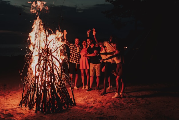 Young Company Dancing Around Bonfire On Beach.