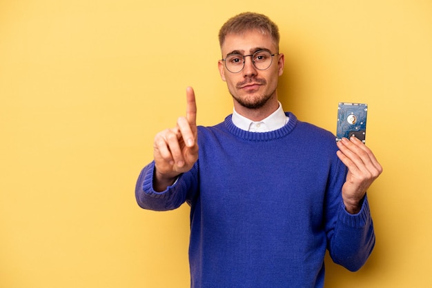 Young computer man isolated on yellow background showing number one with finger.