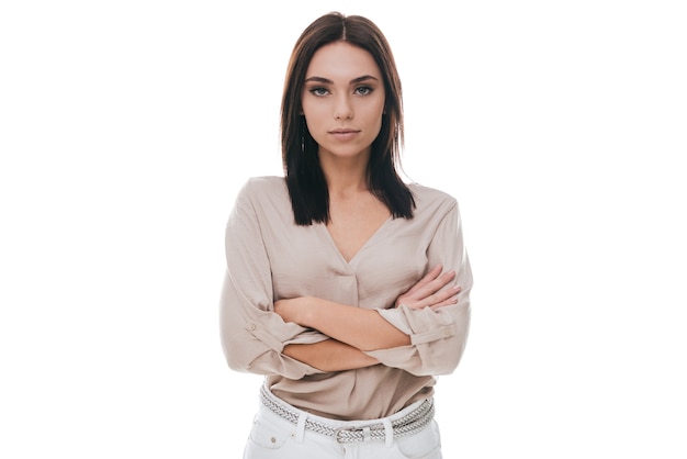 Young and confident. Attractive young woman in smart casual wear keeping arms crossed and looking at camera while standing against white background