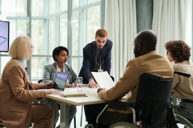 Young confident chief executive officer pointing at document on desk