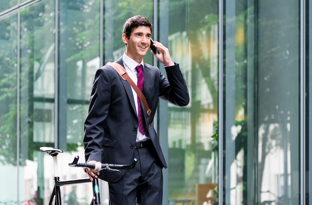 Young confident man  talking on mobile phone after bike commutin