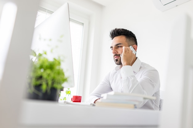 Young confident man working in modern office full of light