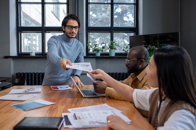 Young confident speaker passing document to colleague before presentation