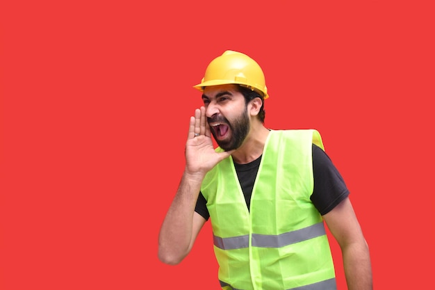 young construction worker shouting looking aside over red background indian paistani model