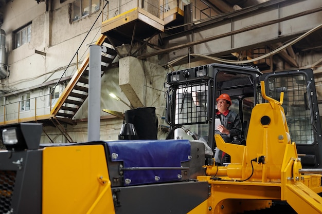 Young contemporary female worker operating construction machine