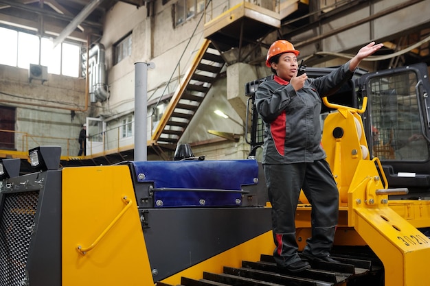 Young contemporary technician of industrial plant speaking in walkie talkie