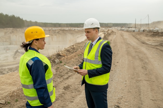 Young contractor with tablet talking to female builder